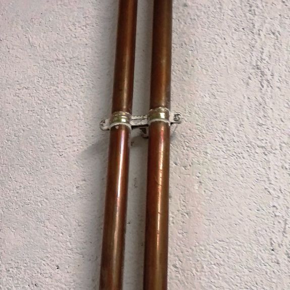 Aplicación de abrazadera metálica doble M6 AD para fijación segura de dos tuberías