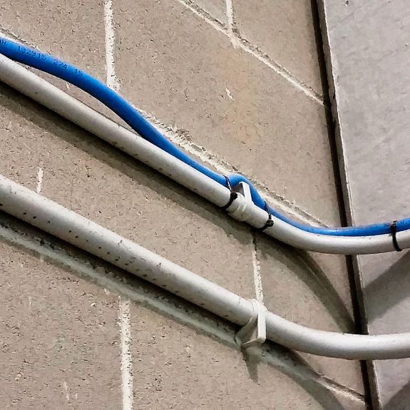 Fijación de tubos con grapas plásticas para organización de cables en pared