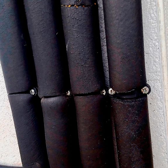 Imagen de aplicación de abrazaderas metálicas dobles gas M6 GD sujetando varias tuberías con aislamiento térmico mediante tornillos para instalación segura en pared