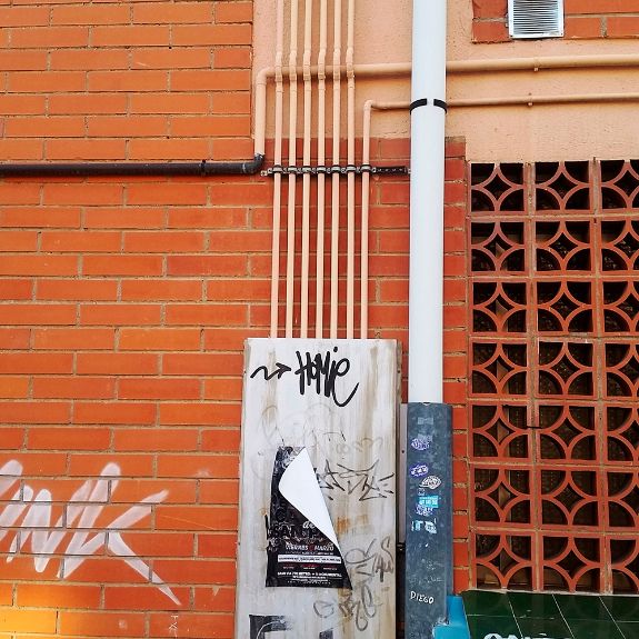 Instalación de tubos con soporte isofónico SMI en fachada de ladrillo