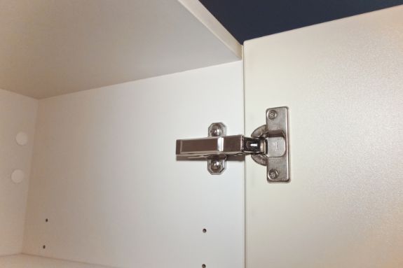 Bisagra metálica instalada en puerta de mueble de madera