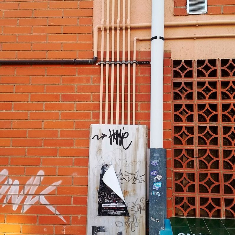 Instalación de tubos con soporte isofónico SMI en fachada de ladrillo