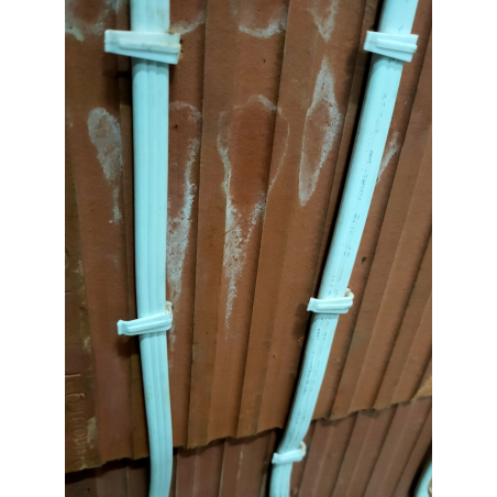 Fijación de cables planos con clips plásticos para organización en pared