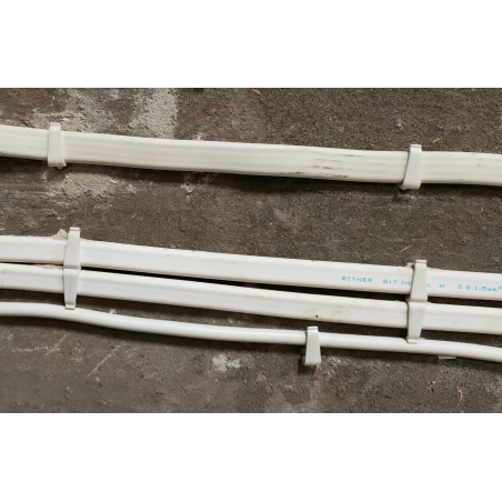 Fijación de cables planos con clips plásticos para organización en pared