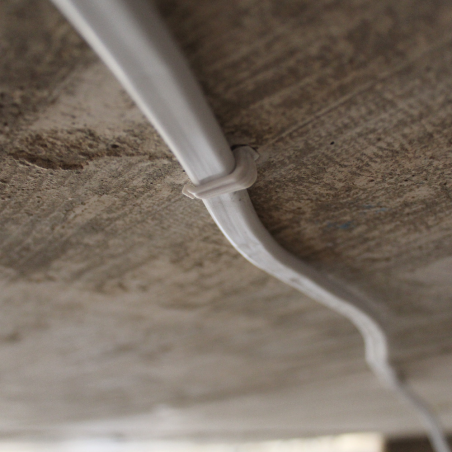 Fijación de cables planos con clips plásticos para organización en pared