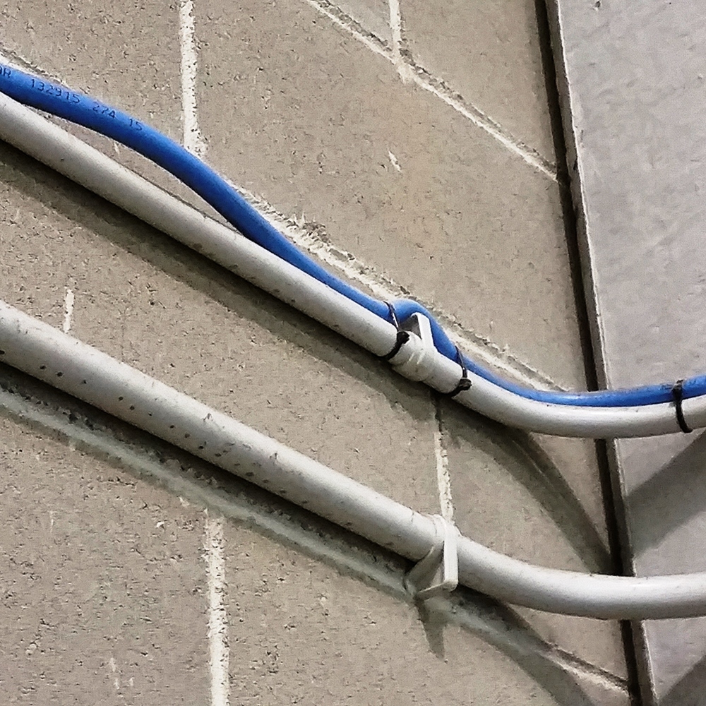 Fijación de tubos con grapas plásticas para organización de cables en pared