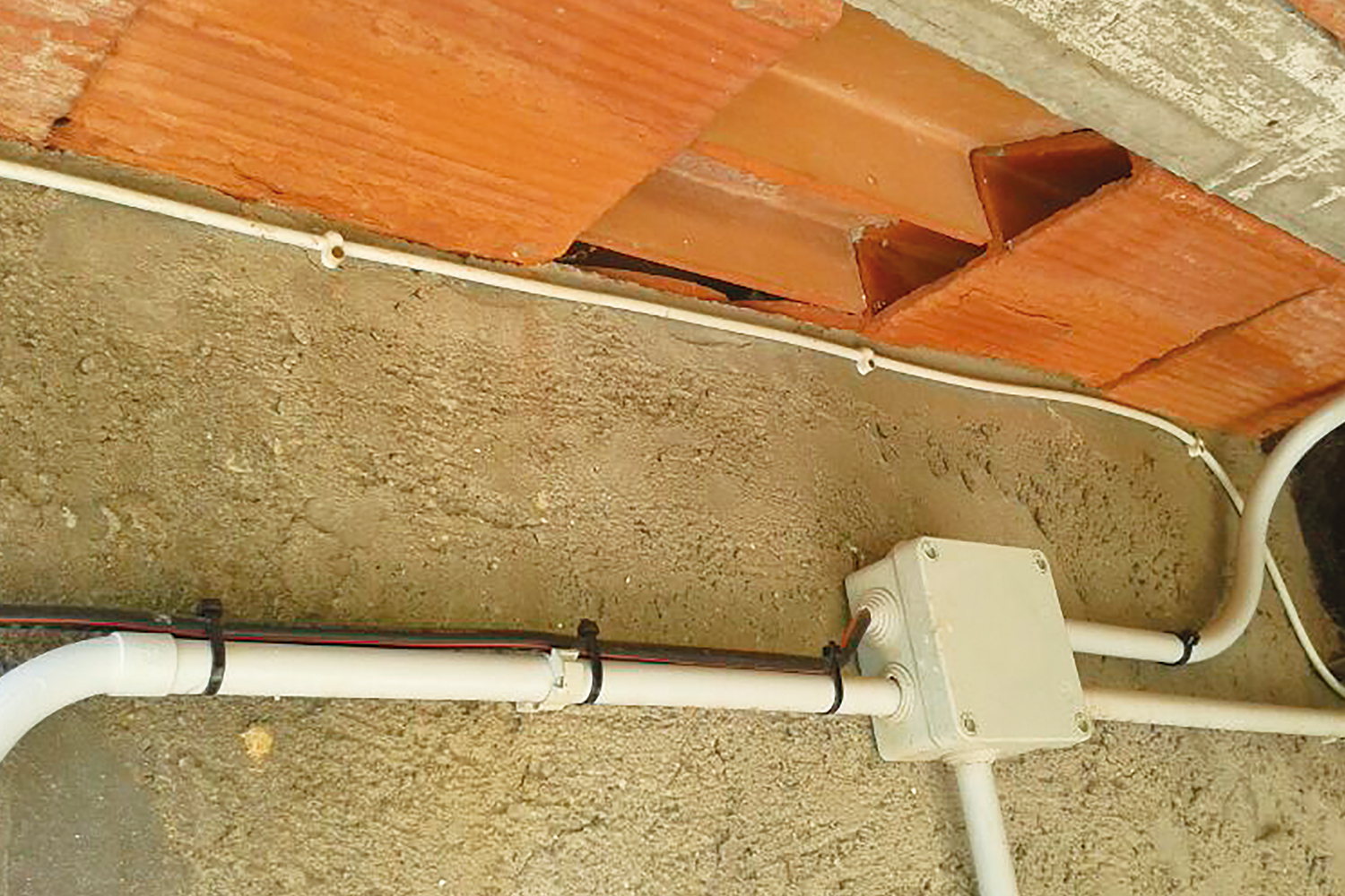 Fijación de tubos y cables en pared con grapas Plastigrap PLG y bridas plásticas