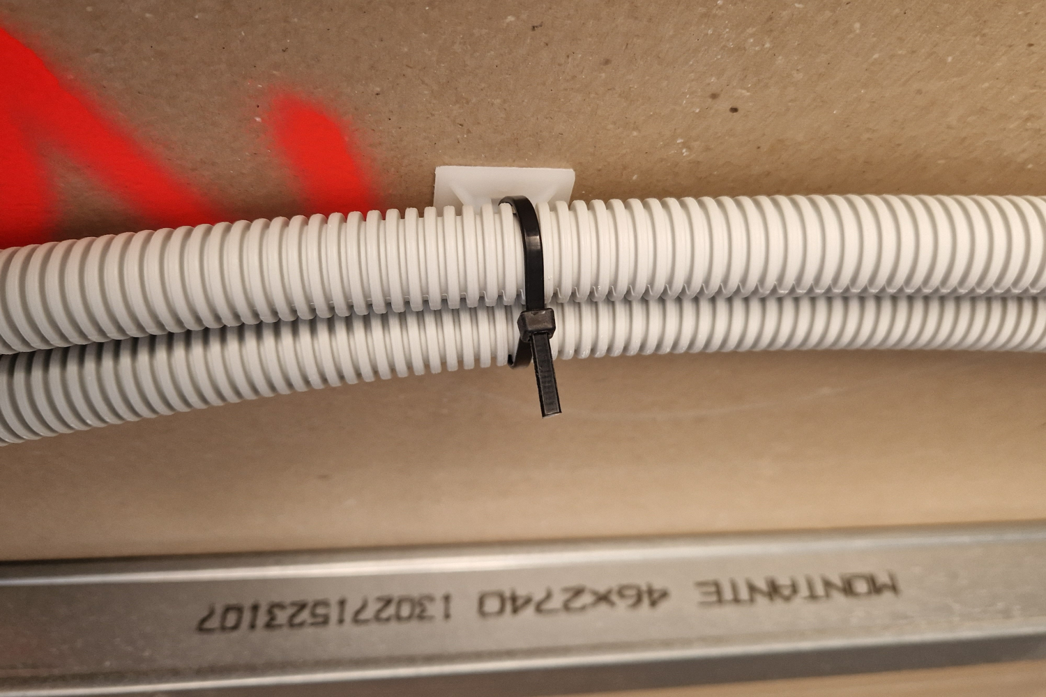 Aplicación de base adhesiva con brida para fijación de tubo corrugado