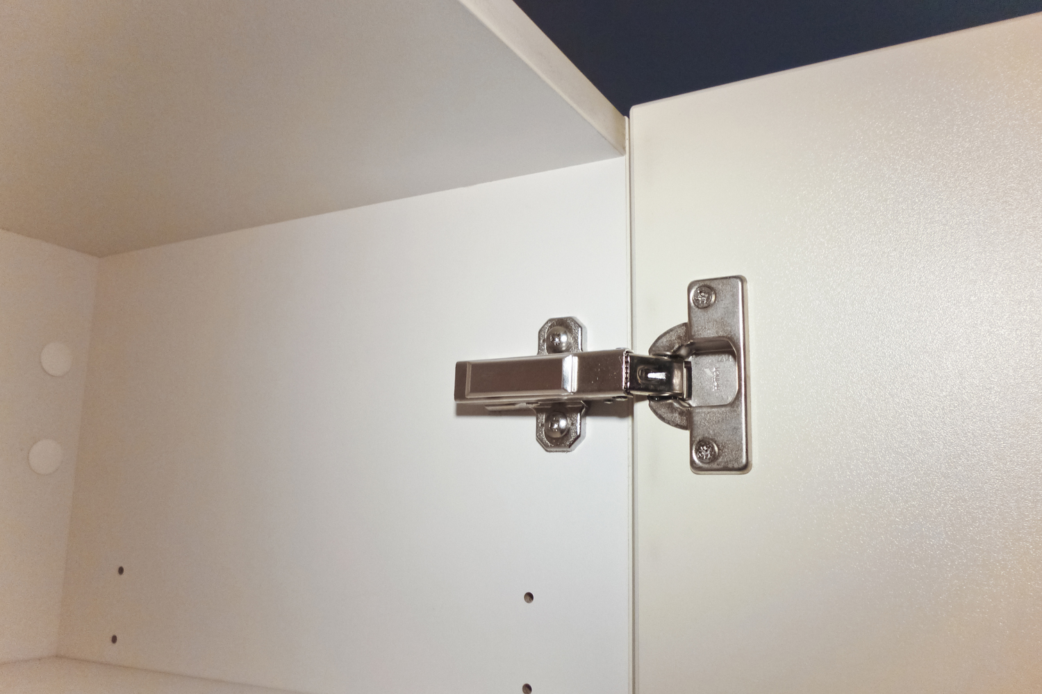 Bisagra metálica instalada en puerta de mueble de madera