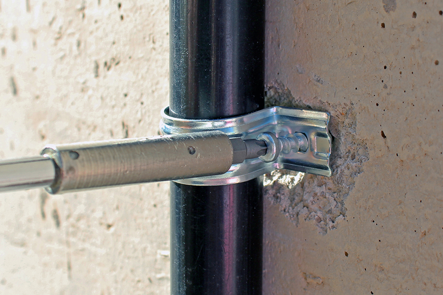Instalación de abrazadera metálica con tornillo BTS4 en pared de hormigón