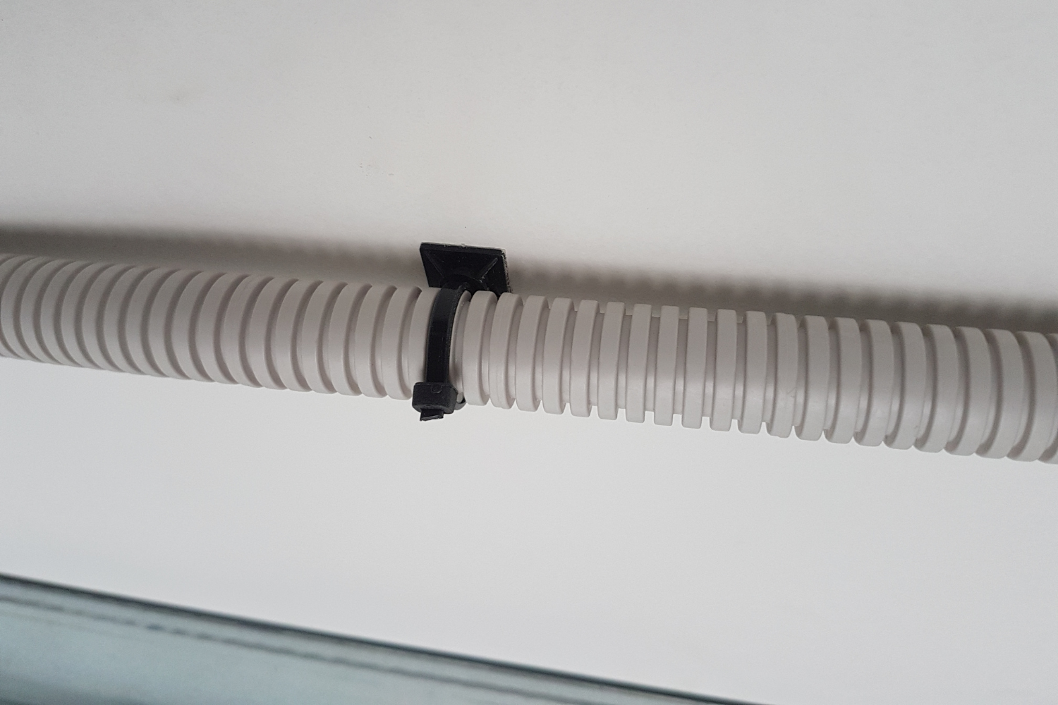 Aplicación de base adhesiva con brida para fijar tubo corrugado