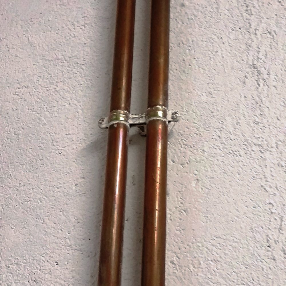 Aplicación de abrazadera metálica doble M6 AD para fijación segura de dos tuberías