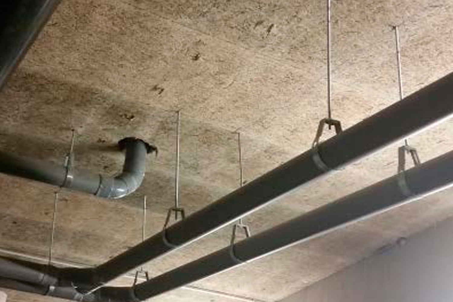 Imagen de aplicación del tornillo para hormigón BTS6: suspensión de tuberías desde el techo de hormigón.