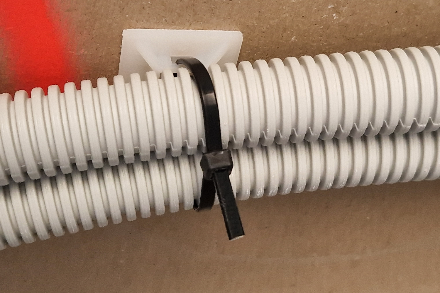 Aplicación de base adhesiva con brida para fijación de tubo corrugado
