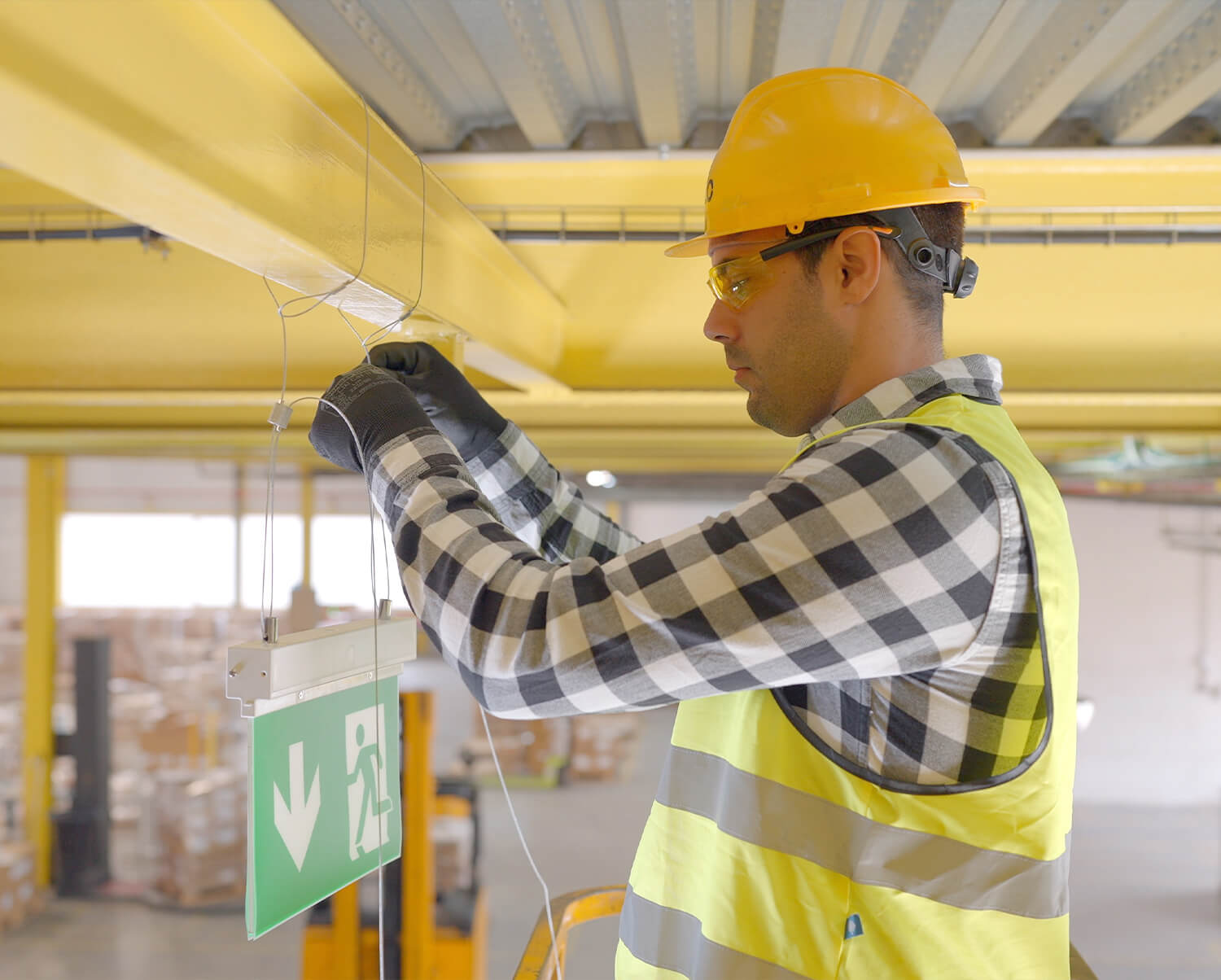 Instalador colgando un cartel en una viga con el sistemade fijación suspendida de CELO