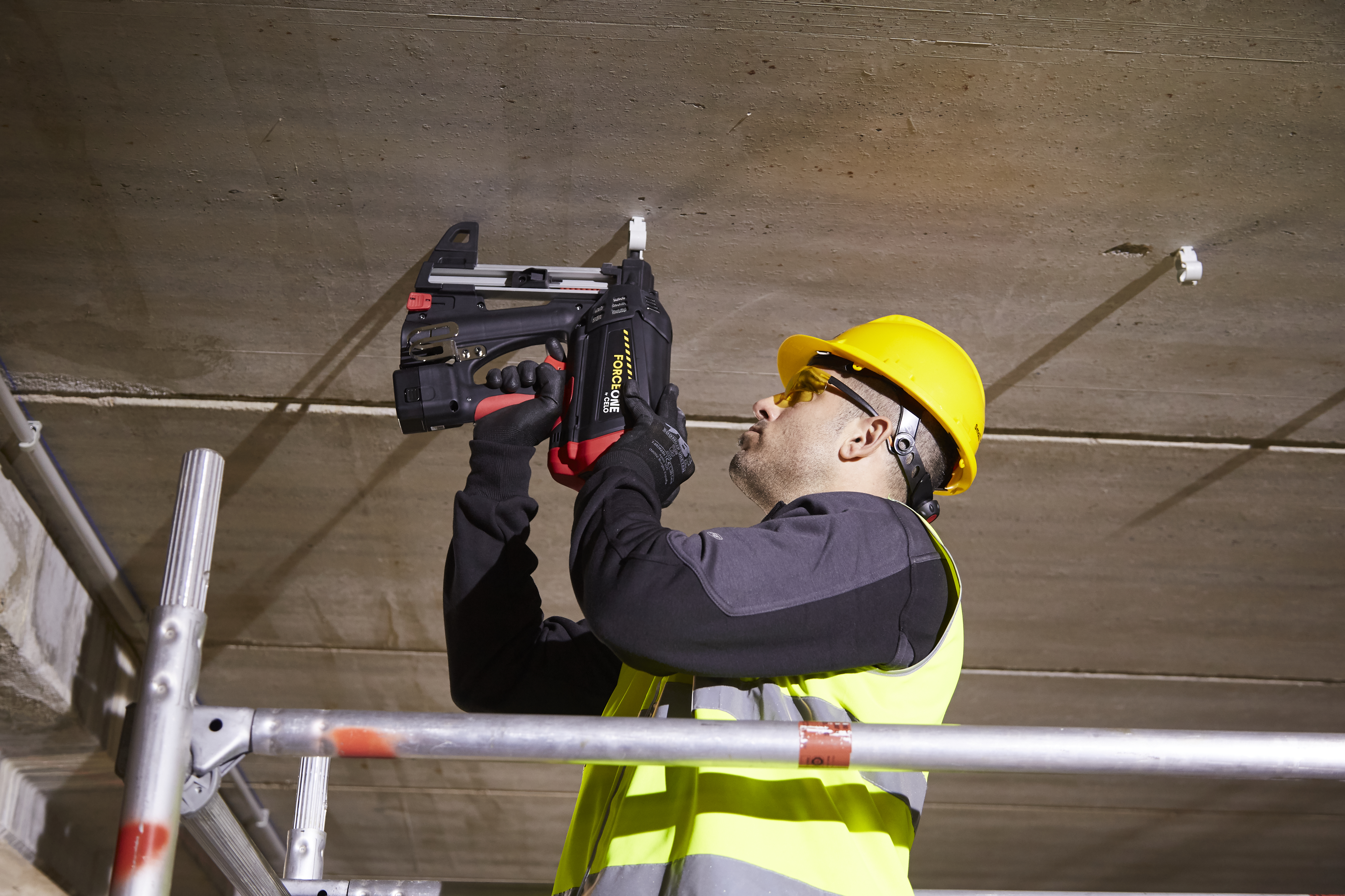 instalador de sistemas de sujeción fijando abrazaderas en el techo con una pistola de clavos