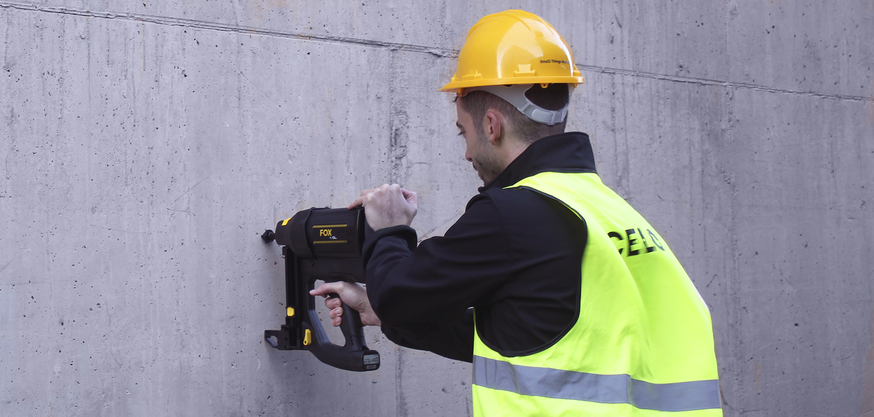 Instalador clavando una fijación en la pared con una pistola de clavos a gas
