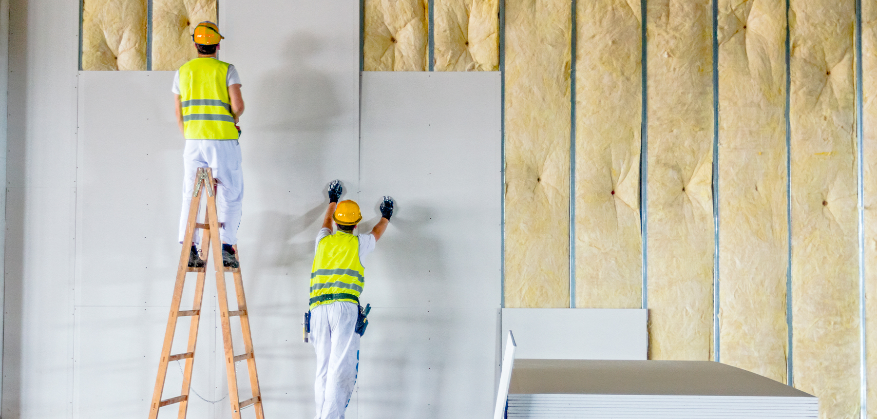 Instaladores fijando una placa de pladur sobre una pared con aislamiento y perfiles de aluminio