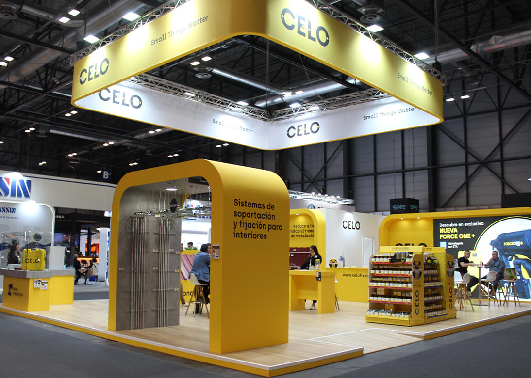 Stand de CELO en la feria Matelec con estructura y mobiliario amarillo y expositores de productos de fijación y suportación