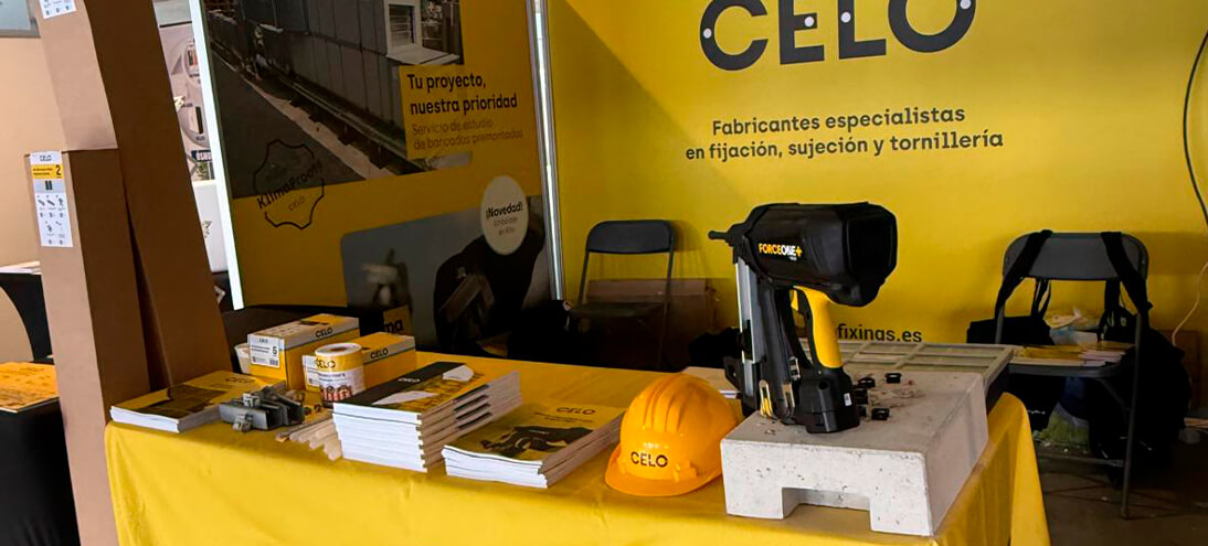 Stand de CELO en la feria C&R con estructura y mostradores amarillos y expositores de productos de fijación y suportación