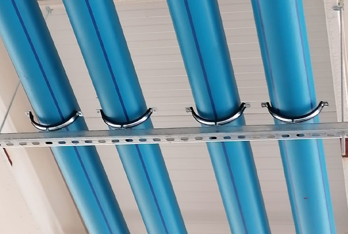 sistema de sujeción de tuberías con abrazaderas metálicas sobre un perfil de aluminio en suspensión